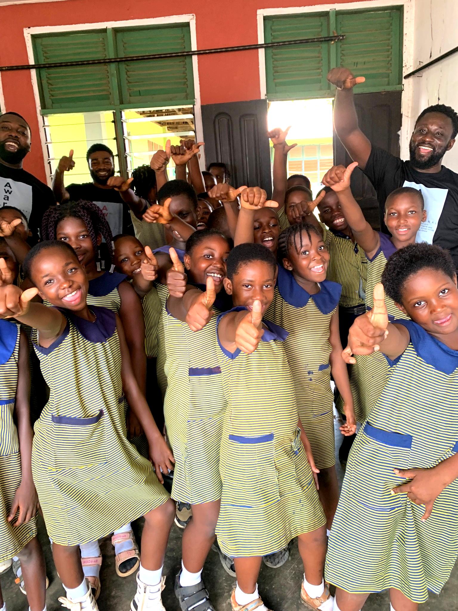 Schoolchildren in Ghana smiling and giving thumbs up during an Aware International session