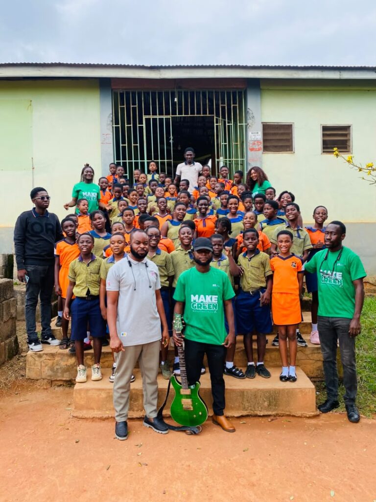 Pupils and Make It Green facilitators assembled in a school compound with watering cans